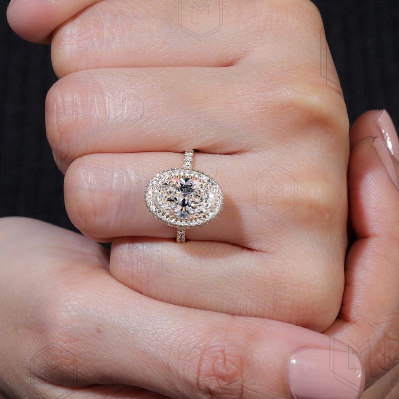 May include: A gold engagement ring with a large oval-shaped diamond surrounded by a double halo of smaller diamonds.