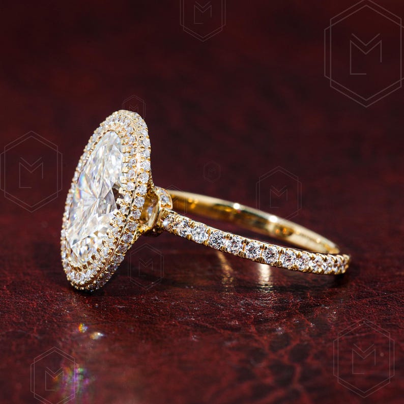 May include: A gold engagement ring with a large oval-shaped diamond surrounded by a double halo of smaller diamonds. The band is also set with smaller diamonds.