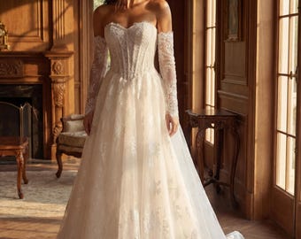 Vestido de novia corte A de encaje color marfil, con corpiño de corsé sin tirantes y cola capilla.