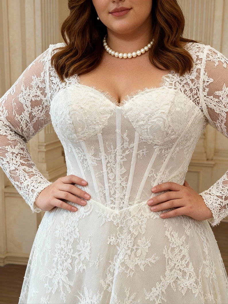 May include: A white floor-length gown featuring a sweetheart neckline, a structured corset-style bodice with vertical boning, and long sheer lace sleeves. The dress is adorned with intricate floral lace overlays and a full skirt with lace detailing.