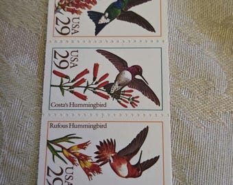 May include: A sheet of 29-cent postage stamps from the United States Postal Service, 1991. Each stamp features a different hummingbird species: Ruby-throated, Broad-billed, Costa's, Rufous, and Calliope Hummingbird. The stamps are rectangular with a white background.