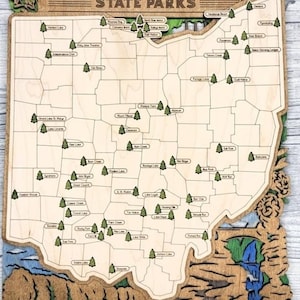 May include: Wooden Ohio State Parks map with laser-cut details. The map features the state outline, park locations marked with trees, and the text "OHIO STATE PARKS" at the top. Decorative elements include a bird and floral designs.