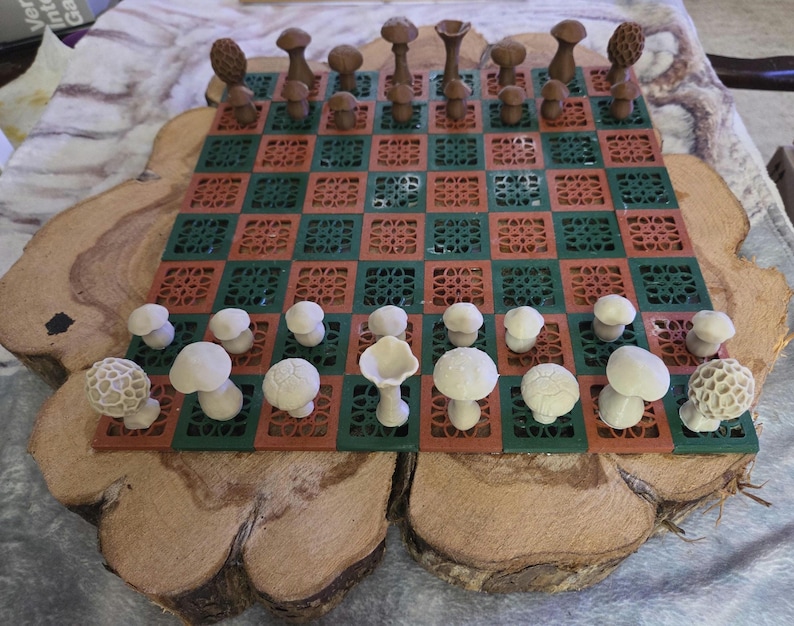 May include: A unique chess set featuring mushroom-shaped pieces on a green and red checkered board. The board is set on a wooden base. The chess pieces are various shades of brown and white.