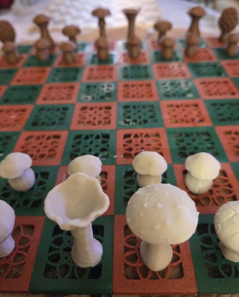 May include: A unique chess set featuring mushroom-shaped pieces in shades of brown and white. The board has a red and green checkered pattern. The pieces are arranged on the board, ready for play.