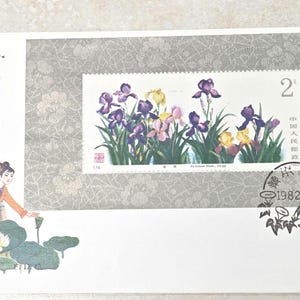 May include: A commemorative postage stamp featuring purple and yellow iris flowers, set against a gray lace-patterned background. The stamp includes the number 2, Chinese characters, and a postmark dated 1982.5.20. Two figures in a boat are illustrated on the left.