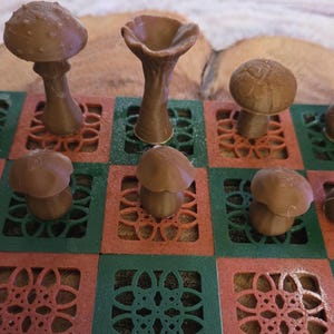 May include: A brown mushroom-themed chess set. The chess pieces are various mushroom shapes, set on a red and green patterned board. The pieces are a light brown color, and the board has a decorative floral design.