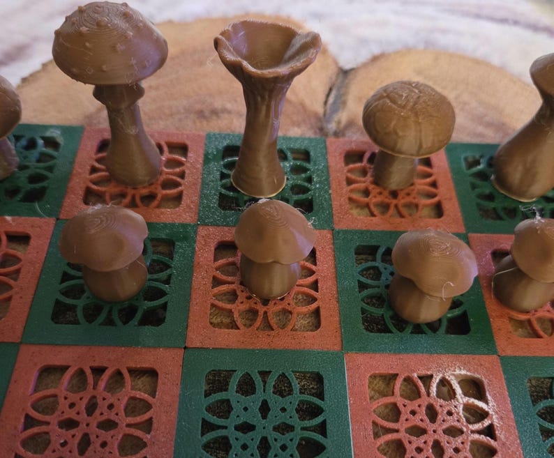 May include: A brown mushroom-themed chess set. The chess pieces are various mushroom shapes, set on a red and green patterned board. The pieces are a light brown color, and the board has a decorative floral design.