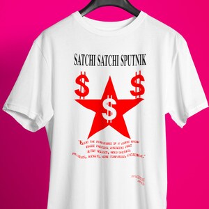 May include: White t-shirt with a red star and dollar signs. The text "Satchi Satchi Sputnik" is printed above the star. The text "Beyond the contours of a young brand, there's a vision, a drive, and the audacity, and details, strategy, work, your company deserves." is printed below the star.