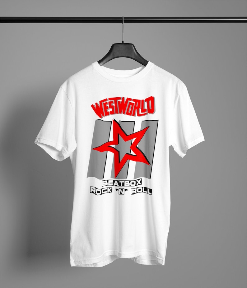 May include: White t-shirt with a red and gray graphic design. The graphic features the text "WESTWORLD" in red, a red star, and the text "BEATBOX ROCK 'N' ROLL" in black.