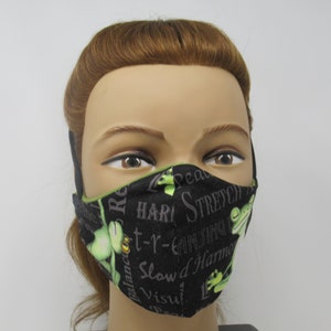 May include: Black face mask with green frogs and text that says "Peace, Balance, Root, Hari, t-r-e-a-t, Can-t-ing, Stretch, Slow d Harm, Visual, L".