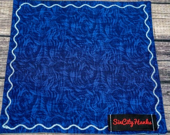 May include: A blue pocket square with a white scalloped border and a black label that says "Sin City Hanks".
