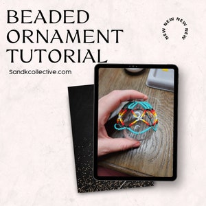 May include: A tablet displays a beaded ornament tutorial. The ornament is clear with a colorful beaded design in red, yellow, and turquoise. The text "BEADED ORNAMENT TUTORIAL" and "Sandkcollective.com" are visible.