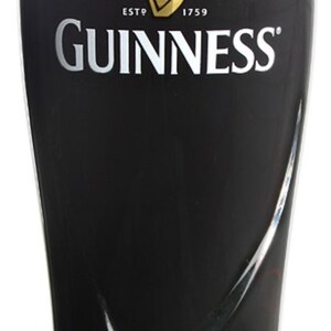 May include: A glass of Guinness stout with a thick head of foam. The glass has the Guinness logo and the text "ESTD 1759" printed on it.