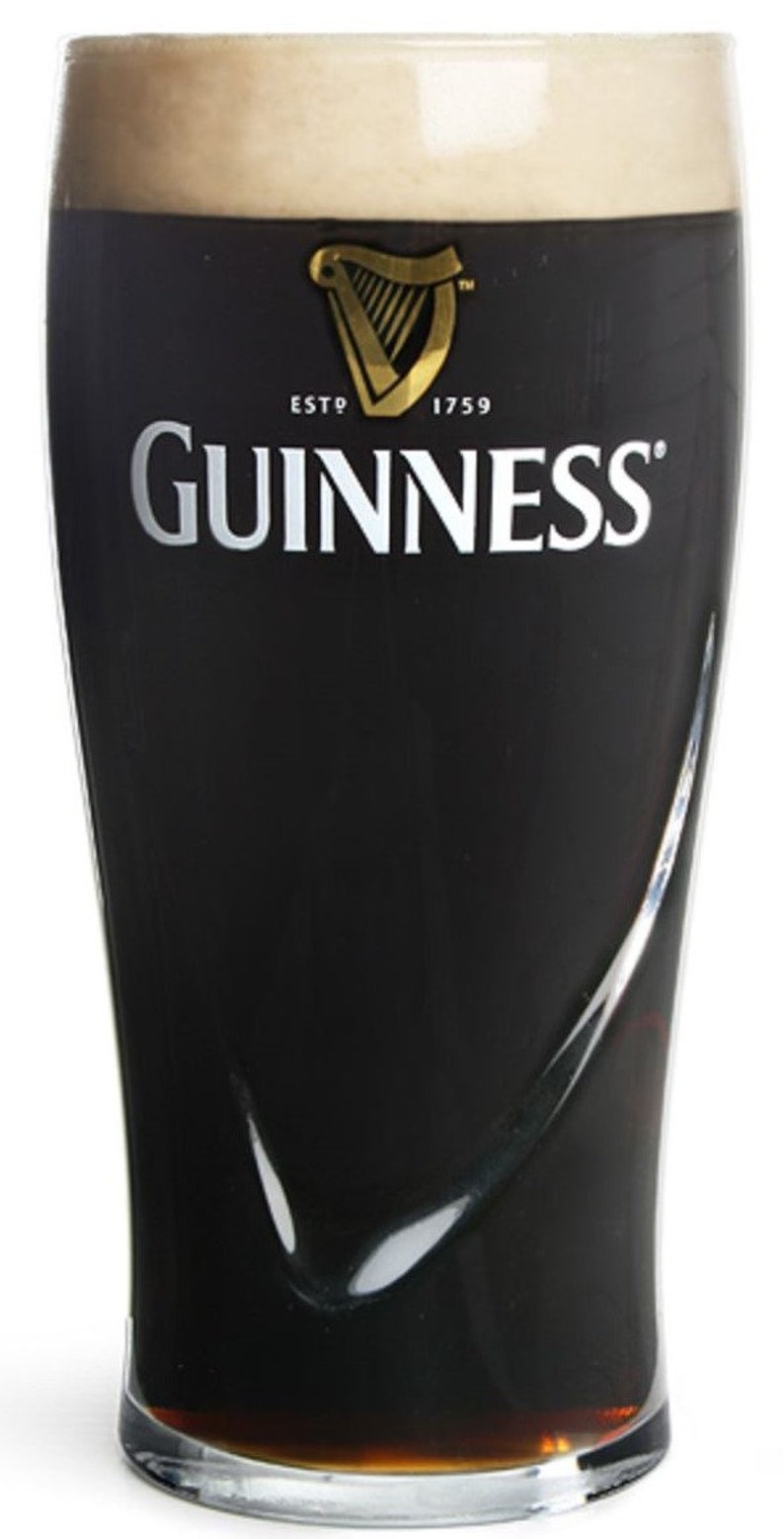 May include: A glass of Guinness stout with a thick head of foam. The glass has the Guinness logo and the text "ESTD 1759" printed on it.