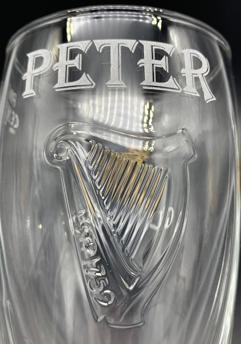 May include: A clear glass pint glass with the name "PETER" etched on the top and a harp logo with "Est. 1759" etched on the bottom.