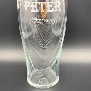 May include: A clear glass pint glass with the name "PETER" etched on the front. The glass features a raised, etched harp design with the text "ESTD 1778" below it.