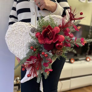 Corona a forma di cuore con amarilli color bordeaux. Corona invernale a forma di cuore con fiori color bordeaux. Corona natalizia a forma di cuore da 23 pollici. Corona a forma di cuore di Florina.