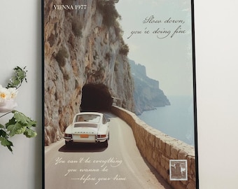 May include: A framed poster featuring a white Porsche driving through a tunnel on a winding road along a cliffside. The text on the poster reads "Slow down, you're doing fine" and "You can't do everything you wanna be - before your time".