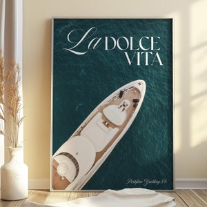 Könnte beinhalten: Eine weiße Yacht mit dem Text "La Dolce Vita" und "Portofino Yachting Co." auf einem blaugrünen Hintergrund.