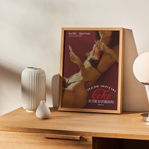 May include: A framed poster featuring a woman in a bikini drinking from a can of Coke. The poster reads "Please don't do Coke in the bathroom without me."