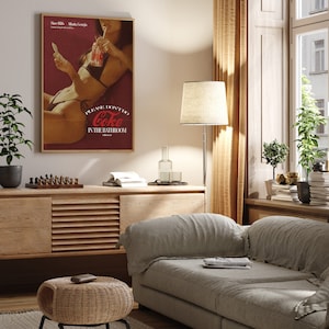 May include: A vintage-style poster featuring a woman holding a glass of Coca-Cola. The poster has a red background with the text "Please don't do Coke in the bathroom".