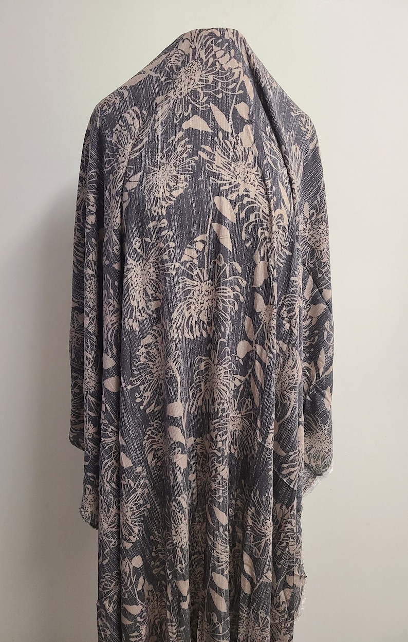 May include: A dark gray fabric with a light brown floral print. The fabric has a textured surface and a subtle sheen.