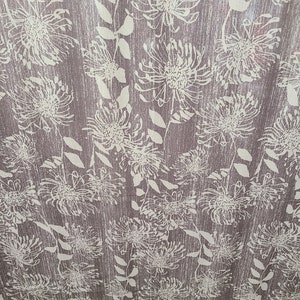 May include: A brown fabric with a white floral pattern. The flowers are stylized and resemble pinecones.