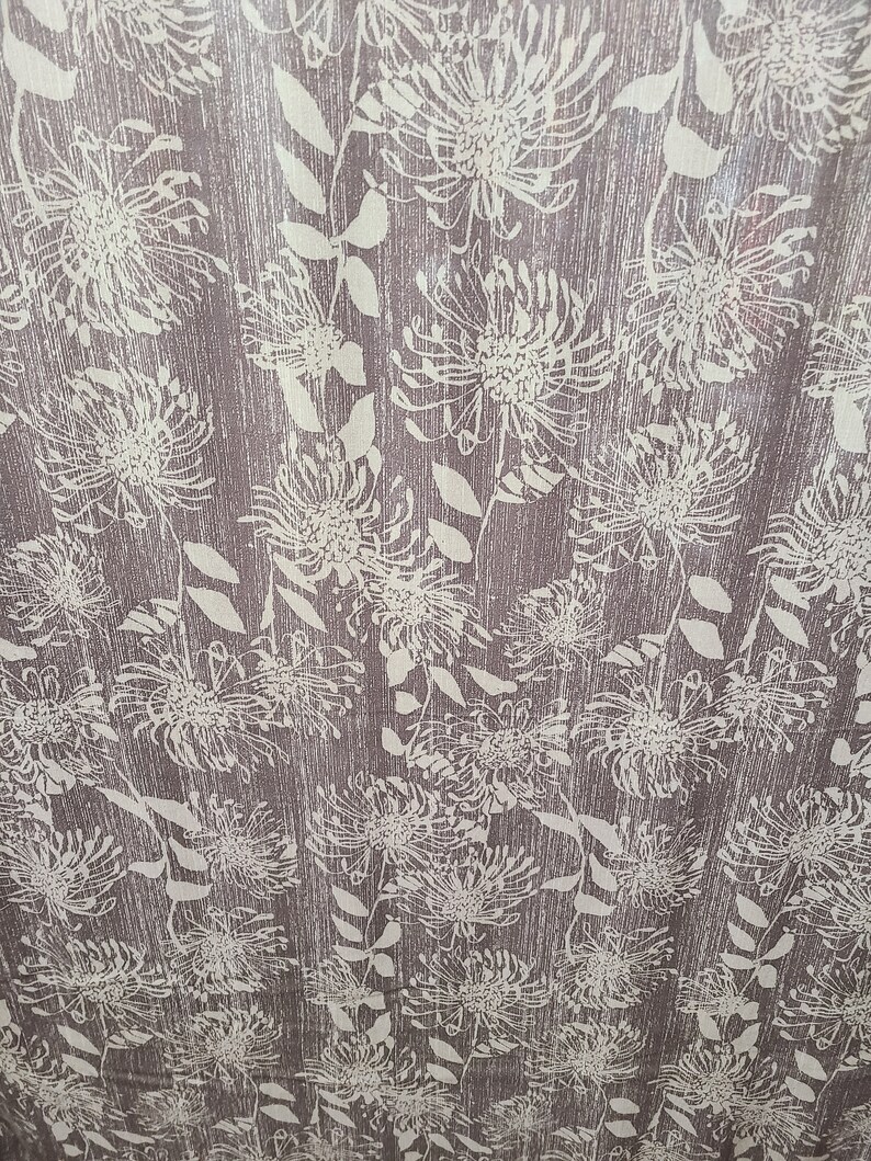 May include: A brown fabric with a white floral pattern. The flowers are stylized and resemble pinecones.