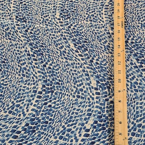 May include: Blue and white fabric with a repeating pattern of small, irregular shapes. A wooden ruler, marked in inches, runs vertically along the right side of the fabric, showing measurements up to 31 inches.