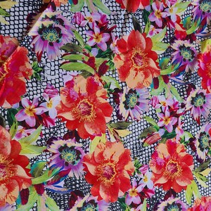 May include: A vibrant floral fabric featuring large red and orange flowers with yellow centers, surrounded by green leaves and smaller pink and purple blossoms. The background has a black and white grid pattern.