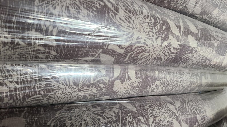 May include: Rolls of brown fabric with a white floral pattern. The fabric is wrapped in clear plastic.
