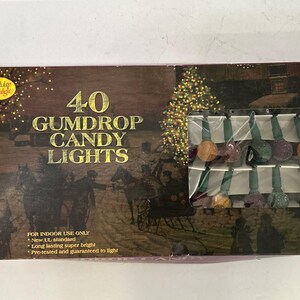 May include: A box of 40 Gumdrop Candy Lights for indoor use. The box features a winter scene with a horse-drawn carriage and a Christmas tree. The lights are multi-colored and pre-tested.