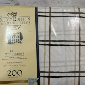 May include: A full fitted sheet set in a clear plastic package. The sheet has a white background with a plaid pattern in black, brown, and tan. The packaging includes the text "Select Edition" and "Mostly Cotton".