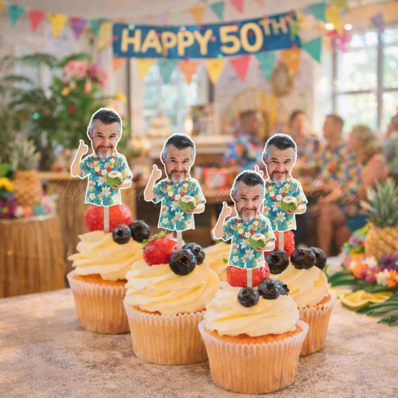 May include: Four cupcakes topped with white frosting, fresh strawberries, blueberries, and paper cutouts of a man wearing a floral shirt and holding a coconut. The cutouts feature a smiling face with a beard and a thumbs-up gesture.