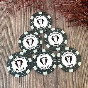 May include: Six circular black and white poker chips featuring a tuxedo graphic in the center. Each chip is personalized with a name and a title: Best Man Joe, Groomsman Paolo, Groomsman Olly, Groomsman Henry, Groom Mikey, and Groomsman Josh.