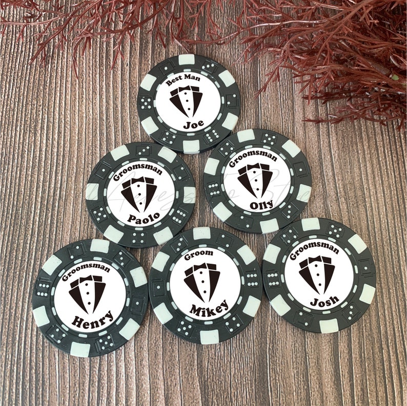 May include: Six circular black and white poker chips featuring a tuxedo graphic in the center. Each chip is personalized with a name and a title: Best Man Joe, Groomsman Paolo, Groomsman Olly, Groomsman Henry, Groom Mikey, and Groomsman Josh.