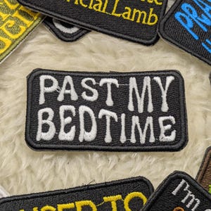 May include: Black and white embroidered patch with the text "Past My Bedtime" in white lettering on a black background.