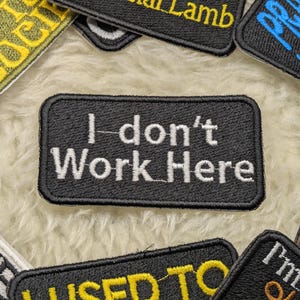 May include: Black embroidered patch with white text that reads "I don't Work Here".