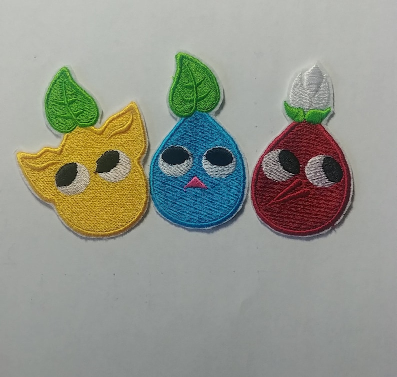 May include: Three embroidered iron-on patches featuring cartoon characters with large eyes. The characters are a yellow lemon, a blue teardrop, and a red teardrop. Each character has a green leaf on top.