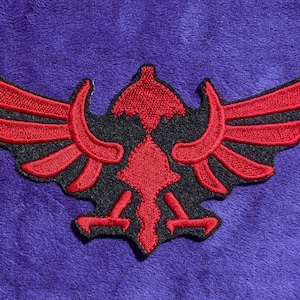 May include: Red and black embroidered patch of a stylized eagle with wings spread wide.
