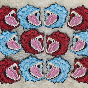 May include: Twelve embroidered iron-on patches featuring a stylized image of a roaring mouth with sharp teeth. Six patches are red and six are blue.