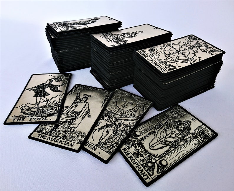 May include: A set of black and silver tarot cards with images of The Fool, The Magician, The Sun, and The Hierophant. The cards are stacked in a pile, with the top card showing the Wheel of Fortune.