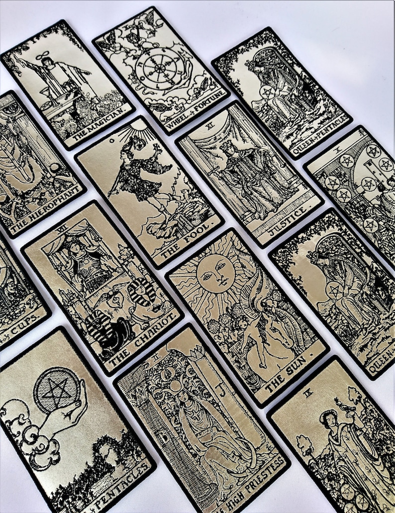 May include: A set of tarot cards with black and white illustrations on a silver background. The cards are arranged in a random pattern. The cards include The Magician, The Hierophant, The Chariot, The Fool, The Sun, Wheel of Fortune, Justice, Queen of Pentacles, and High Priestess.