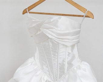 Abito da sposa a corsetto, lunghezza mini, gonna voluminosa e vaporosa, stile boho con spalline sottili.