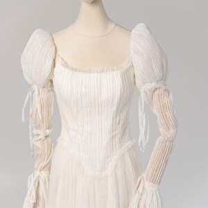 a mannequin wearing a white dress with long sleeves