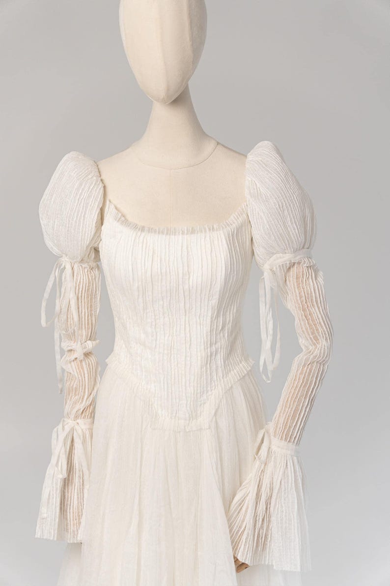 a mannequin wearing a white dress with long sleeves