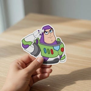 May include: A die-cut sticker featuring Buzz Lightyear from Toy Story. The sticker shows Buzz in his signature space ranger uniform, saluting. The design includes green, purple, white, and gray colors, with the number "000" on the chest.