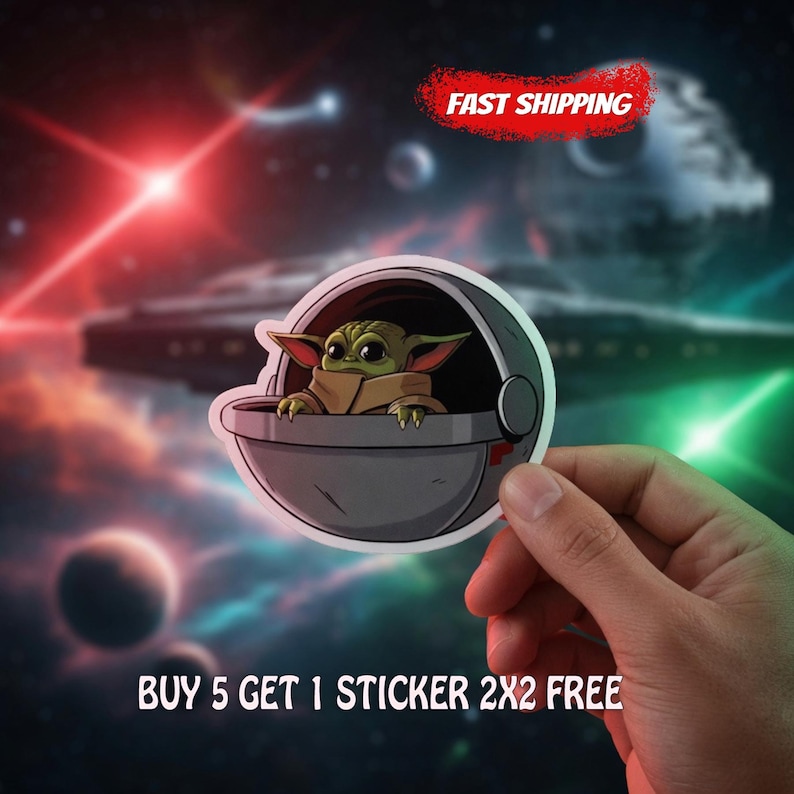 May include: A die-cut sticker featuring a green, large-eared creature with big black eyes sitting inside a gray, spherical floating pod. The sticker has a white border and is set against a dark, out-of-focus space background with stars.