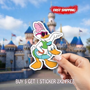 May include: A white sticker featuring Daisy Duck wearing heart-shaped sunglasses, a green top, and a blue swim ring, with Donald Duck. The background shows a castle. Text reads: "BUY 5 GET 1 STICKER 2X2 FREE".