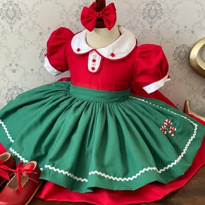Könnte beinhalten: Ein rotes und grünes Weihnachtskleid mit weißem Kragen und Zuckerstangen-Stickerei. Das Kleid hat einen vollen Rock und ist perfekt für eine Weihnachtsfeier.